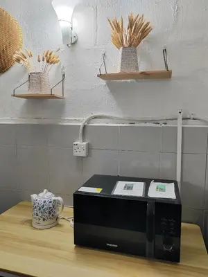 a black microwave on a wooden counter in a kitchen at RAHIM HOMESTAY KUALA KANGSAR in Kuala Kangsar