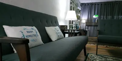 a living room with a green couch with two pillows at RAHIM HOMESTAY KUALA KANGSAR in Kuala Kangsar