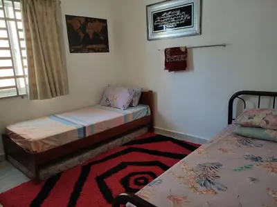 a bedroom with two beds and a rug at Nurul Saadah Lunas in Lunas