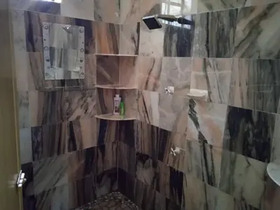 a bathroom with a stone wall with a shower at Enalys Homestay untuk orang islam sahaja in Kampung Bota Kiri