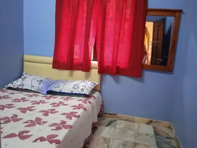 a bedroom with a bed with red curtains and a mirror at Enalys Homestay untuk orang islam sahaja in Kampung Bota Kiri