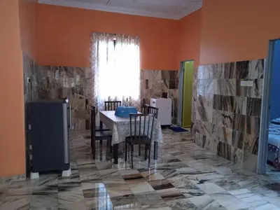 a dining room with a table and chairs and orange walls at Enalys Homestay untuk orang islam sahaja in Kampung Bota Kiri