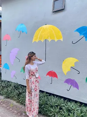 a woman standing in front of a painting of umbrellas at SURIA BEACH RESORT Pangkor in Pangkor