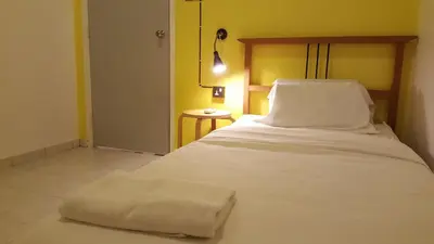 a bedroom with a white bed with a wooden headboard at Tulip Hotel in Ipoh