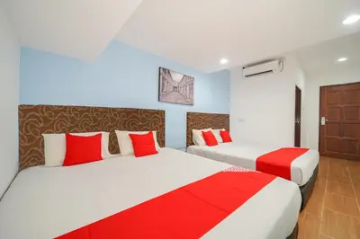 two beds in a room with red and white at JMA FERRINGHI BEACH HOTEL in Batu Ferringhi