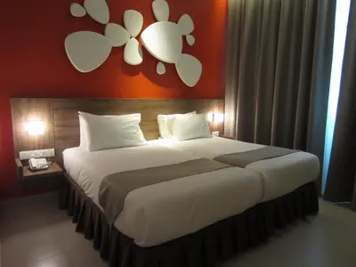 a bedroom with a large bed with an orange wall at D Hotel in Seri Iskandar