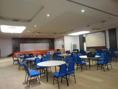 a room filled with tables and chairs with blue chairs at D Hotel in Seri Iskandar