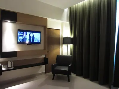 a hotel room with a chair and a television at D Hotel in Seri Iskandar