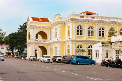 a yellow building with cars parked in front of it at Bishop Hotel in George Town