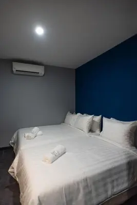 a large white bed with white pillows and a blue wall at Chariton Hotel Bagan in Butterworth