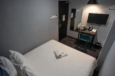 a bedroom with a bed and a desk with a television at Chariton Hotel Bagan in Butterworth