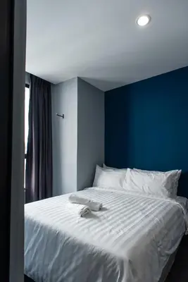 a bedroom with a white bed with a blue wall at Chariton Hotel Bagan in Butterworth