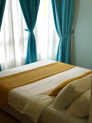 a bed with blue curtains in a bedroom at Mama King’s Homestay@ Palas Horizon in Brinchang
