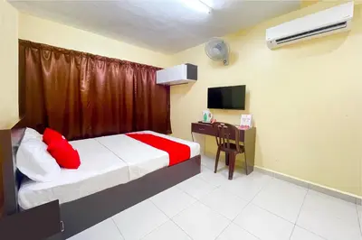 a bedroom with a bed and a desk with a television at OYO 90369 Safari Hotel Lumut in Kampong Pundut