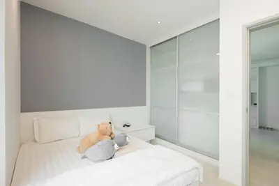 a white bedroom with a teddy bear sitting on a bed at Straits Garden Suites by The Homestay Helper in George Town