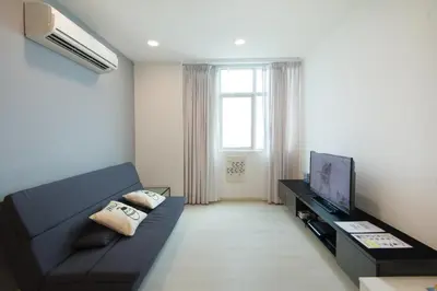 a living room with a black couch and a television at Straits Garden Suites by The Homestay Helper in George Town