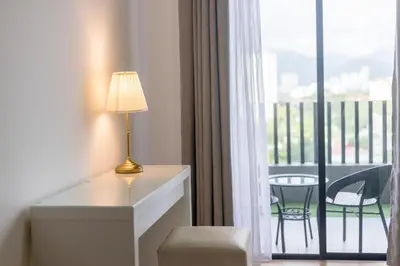 a room with a desk with a lamp and a balcony at Beacon Executive Suite Penang in George Town