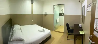 a bedroom with a bed and a desk and a shower at Lih Pin Hotel in Sungai Petani