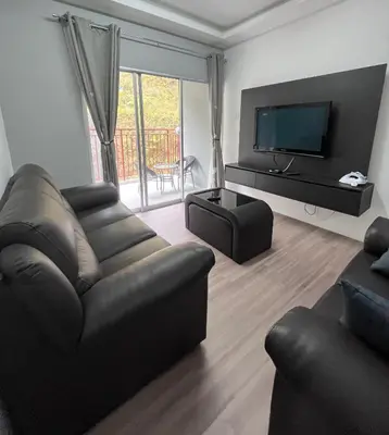 a living room with a leather couch and a television at Cameron Emerald Avenue 2 @ Brinchang in Brinchang