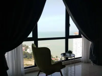 a green chair sitting in front of a large window at Jazz Suites Apartment Penang By Jazz Service Suite in Bagan Jermal