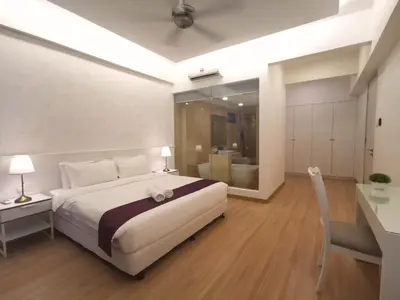 a bedroom with a white bed and a desk and a table at Jazz Suites Apartment Penang By Jazz Service Suite in Bagan Jermal