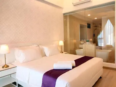 a bedroom with a large white bed and a bathroom at Jazz Suites Apartment Penang By Jazz Service Suite in Bagan Jermal