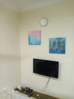 a living room with a tv and a clock on a wall at KH Homestay Comfy N Calm in Seri Manjung