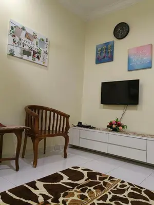 a living room with a chair and a television on a wall at KH Homestay Comfy N Calm in Seri Manjung