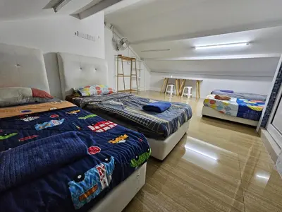 a room with three beds and a table in it at Color Mixed Home Hostel in George Town