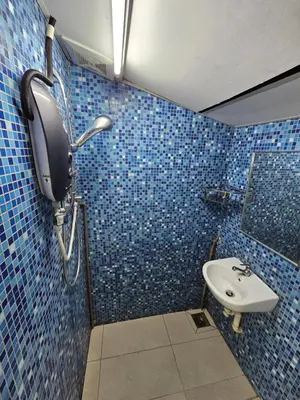 a blue tiled bathroom with a sink and a mirror at Color Mixed Home Hostel in George Town