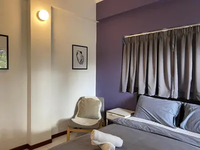 a bedroom with purple walls and a bed and a chair at Aurora Court Service Apartment in George Town