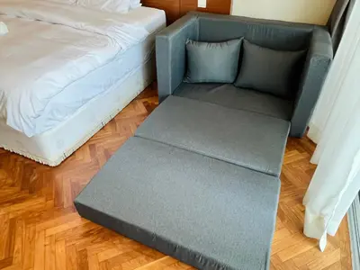 a gray ottoman next to a bed in a room at Instagramable Luxury Suites for Couples or Families • Straits Quay Penang • Sea View Balcony • Private Bathtub in Bagan Jermal