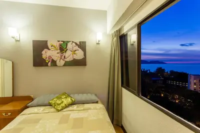 a bedroom with a bed and a large window at Sri Sayang Seaview Holiday Home in Batu Ferringhi