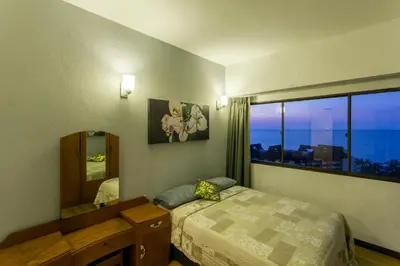 a bedroom with a bed and a mirror and a window at Sri Sayang Seaview Holiday Home in Batu Ferringhi