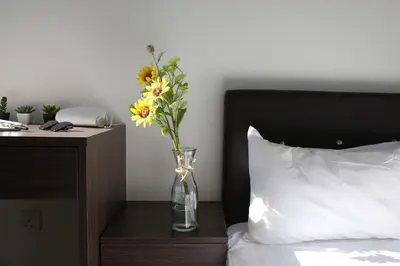 a vase with flowers on a table next to a bed at PLAY at Palas Horizon @ Kea Farm in Cameron Highlands