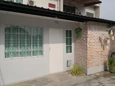 a white house with a door and a brick wall at H&T Vintage Decor Homestay in Ipoh
