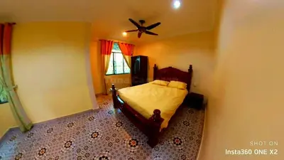 a bedroom with a bed and a ceiling fan at Tuna Cameron Homstay in Brinchang