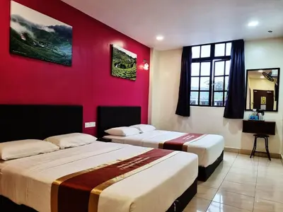 two beds in a room with a red wall at Hotel Sun Birds in Cameron Highlands