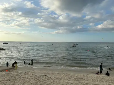 a group of people on the beach near the water at Beach Resort HOME STAY SRI SAYANG 05 APARTMENT BATU FERRINGHI 2BEDROOM in Batu Ferringhi