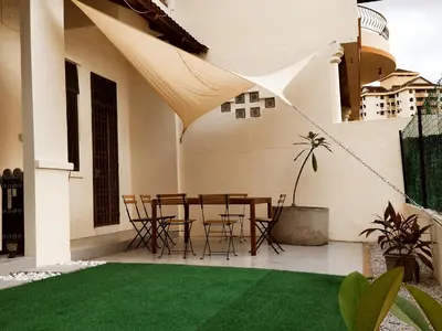 a patio with a table and chairs and green grass at Pinang Beach Cottage @ Ferringhi in Batu Ferringhi