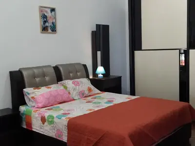 a bedroom with a bed with a comforter and pillows at Pinang Beach Cottage @ Ferringhi in Batu Ferringhi