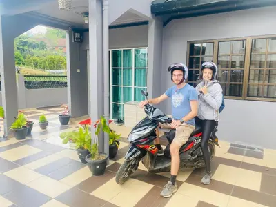 a man and a woman sitting on a motorcycle at 100 Oastel coLiving in Tanah Rata