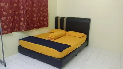 a bed with yellow pillows on it in a room at Taiping Desa Jana Home Stay in Kamunting