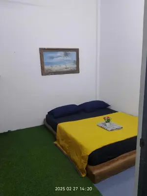 a bedroom with a yellow bed and a green rug at Budget Homestay Impiana Adril in Ipoh