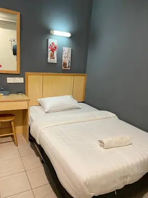 two beds in a room with a desk and a bed at Fresh Hotel Falim in Ipoh