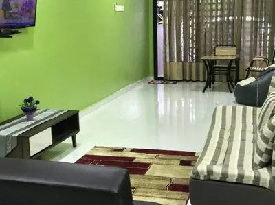 a living room with green walls and a couch and a table at Kinaz homestay in Ipoh
