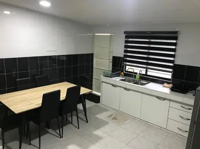a kitchen with a wooden table and black tiles at Kinaz homestay in Ipoh