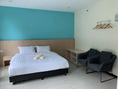 a bedroom with a white bed and two chairs at M Quality Hotel in Gua Musang