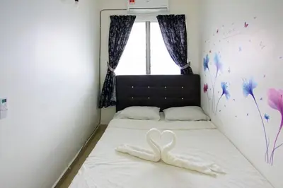 two white swans laying on a bed in a bedroom at Palm Court in Tanjong Tokong