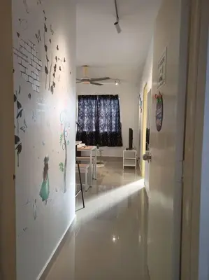 a living room with a white wall with a painting of a woman at Palm Court in Tanjong Tokong